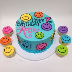 a birthday cake decorated with smiley faces and cupcakes