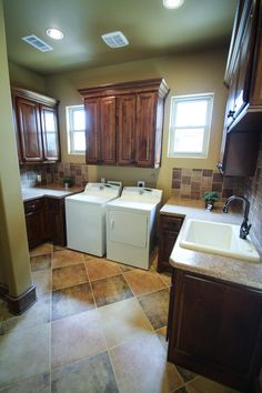 a kitchen with brown cabinets and tile flooring, including a washer and dryer