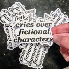 someone holding up a sticker that says cries over fictional characters