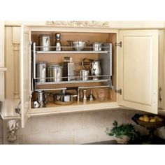 an open cabinet in a kitchen filled with pots and pans