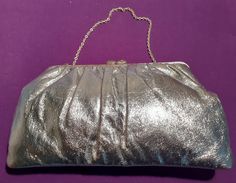 This is a beautifully stylish vintage silver evening purse dating from the 1970's. The purse has a central top purse fastening which is decorated with diamante and there is a silver tone carrying chain. The purse measures 24 cm in width at its widest point and has a depth of 14 cm from the base to the top of the purse clip.   The purse is roomy and can accommodate a standard mobile phone.   The purse clip works beautifully with no issues and is good and strong.   Each side of the purse clip is d Elegant Silver Evening Bag For Vintage Events, Elegant Metallic Evening Bag For Formal Occasions, Elegant Metallic Evening Bag For Formal Events, Vintage Silver Rectangular Clutch, Silver Rectangular Clutch For Cocktail, Silver Rectangular Evening Bag For Cocktail, Rectangular Silver Evening Bag For Cocktail, Glamorous Silver Clutch For Cocktail, Glamorous Silver Cocktail Clutch