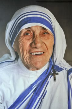 an older woman wearing a blue and white striped headdress smiles at the camera