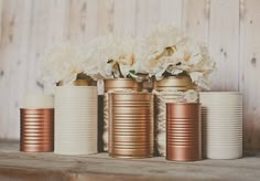 four tin cans with flowers in them sitting on a shelf next to the words diy craft