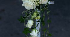 white roses and greenery are arranged in a vase