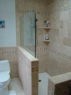 a white toilet sitting next to a walk in shower under a glass door with shelves on the wall