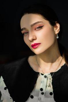 a woman with bright red lipstick on her face and black cardigan jacket over her shoulders