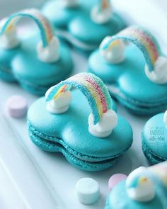 there are many blue macaroons with rainbows on them and marshmallows