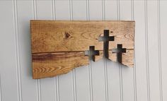 two wooden crosses mounted to the side of a white wall with wood planks on it