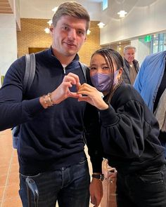 a man and woman standing next to each other in a room with people wearing face masks