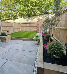 an outdoor patio with landscaping and plants in the back yard, surrounded by wooden fence