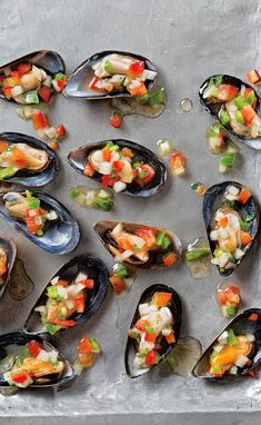 several open mussels with various toppings on a sheet of aluminum foil, ready to be eaten