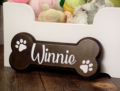 a dog bone shaped toy box with stuffed animals in it and the word winnie written on the front