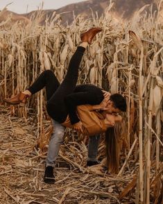 a man and woman kissing in the middle of a corn field