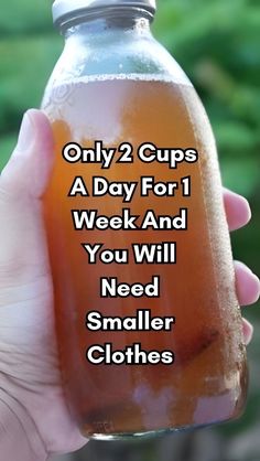 a hand holding a glass jar filled with liquid that says only 2 cups a day for 1 week and you will need smaller clothes