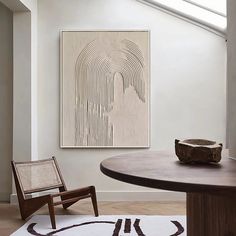 a room with a table, chair and artwork on the wall