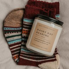 a pair of socks and a candle on top of a white sheet with the words rainy day reading next to it