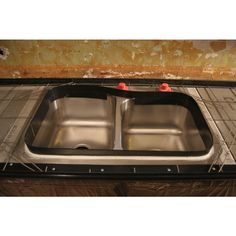 two stainless steel sinks in the middle of a kitchen counter top with no one around them