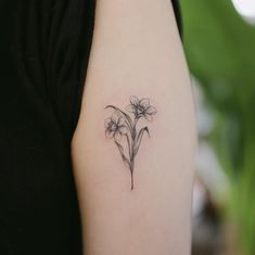 a woman's arm with a small flower tattoo on the left side of her arm