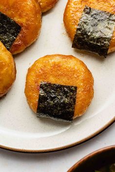 small pastries on a white plate with black squares in them and green leaves around the edges