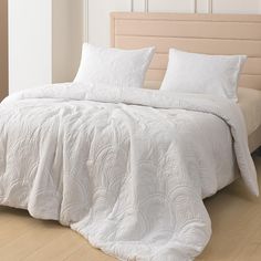 a bed with white comforter and pillows on it