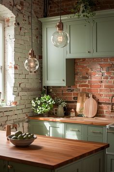 a kitchen with green cabinets and wooden counter tops, hanging lights over the island area