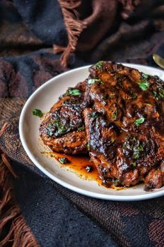 a white plate topped with meat covered in sauce and garnished with parsley