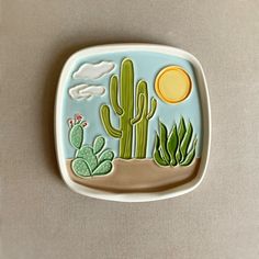 a ceramic plate with cactus and sun on it