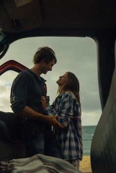 a man and woman standing next to each other in the back of a truck looking at each other