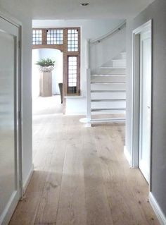 an empty hallway with white walls and wood flooring next to a stair case in front of a window