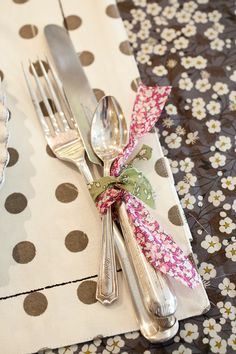 the fork and spoons are wrapped in ribbon on the tablecloth with polka dots