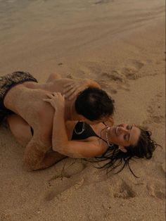 two people are laying on the beach in their bathing suits and one person is holding his arm around the other woman's neck