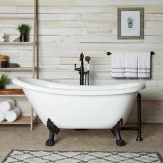 a white bath tub sitting on top of a rug next to a shelf filled with towels