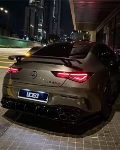 the rear end of a mercedes cla parked in front of a building at night