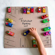 a child's hand writing on a cardboard parking lot