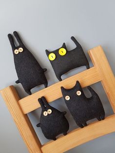 three black cats sitting on top of a wooden frame with yellow eyes and one has two smaller ones behind it