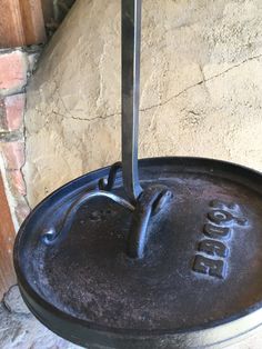 an old cast iron skillet sitting on top of a stone floor next to a brick wall