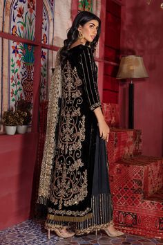 Black Velvet Salwar Kameez Pakistani Wedding Dresses Embrace dignity in this jet black heirloom-worthy classic silk velvet shirt. Pair it with a Salwar/Sharara and Dupatta featuring floral embellished detailing, trimmed with gold Kiran borders. Black Velvet Kameez: NameerabyFarooq presents this beautiful Pakistani wedding dress outfit in jet black to make your day super amazing. The flared long kameez is attractively adorned with thread, kora, Kundan, and the real magic of Zardozi. The fabric us Luxury Black Salwar Kameez With Embroidered Border, Luxury Black Raw Silk Salwar Kameez, Luxury Black Chanderi Salwar Kameez, Luxury Salwar Kameez With Gold Embroidery For Festivals, Luxury Salwar Kameez With Gold Embroidery For Festive Occasions, Luxury Designer Black Salwar Kameez, Luxury Unstitched Dabka Salwar Kameez, Velvet Pakistani Dress 2022, Luxury Black Straight Kurta Salwar Kameez