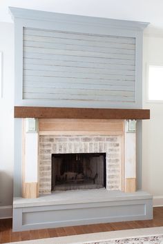 an empty fireplace in a living room with white walls and wood trim on the mantle