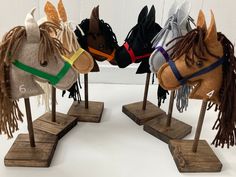 four wooden horse heads are on display in the shape of headdresses with fringes