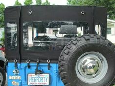 the front end of a blue jeep parked in a parking lot next to a house