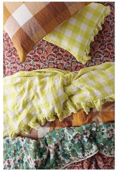 a bed with yellow and white pillows on it's side, next to a green checkered pillow