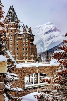 an old castle with snow on the ground and mountains in the backgrouds