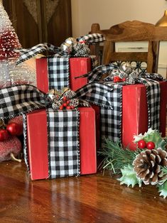 three wrapped presents sitting on top of a table next to pine cones and christmas decorations