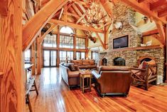 a large living room with wood floors and vaulted ceiling beams, stone fireplace in the center