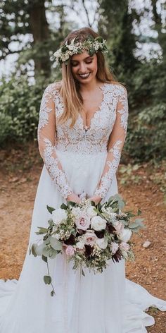 a woman in a wedding dress standing on a path with flowers and greenery around her head