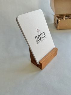 a wooden business card holder with the year 2012 printed on it next to an open box