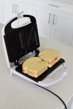 two toasted sandwiches sitting on top of a white counter next to an electric blender