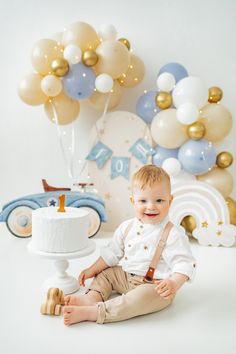 a baby boy sitting in front of a cake