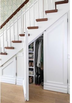 an open closet under the stairs in a house