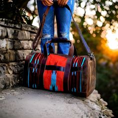 a person standing on top of a brick wall holding a brown and blue striped bag